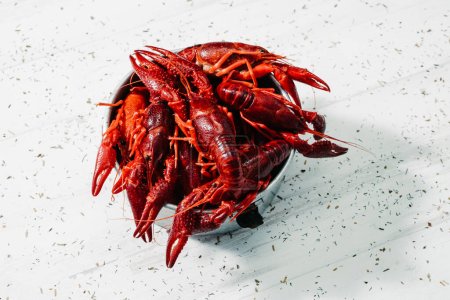 Photo for Closeup of some cooked crayfish served in an old metal container, on a white surface sprinkled with different chopped herbs - Royalty Free Image