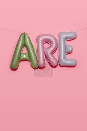 Photo for Some alphabet-shaped balloons of different colors forming the text are hanging from a string on a pink background - Royalty Free Image
