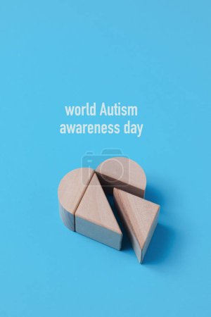 Téléchargez les photos : Gros plan de quelques blocs de construction formant un cœur et le monde du texte journée de sensibilisation à l'autisme, sur un fond bleu - en image libre de droit