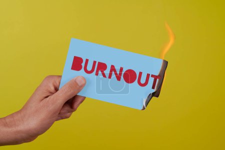 Photo for Closeup of a man holding a blue sign on fire with the text burnout on a yellow background - Royalty Free Image