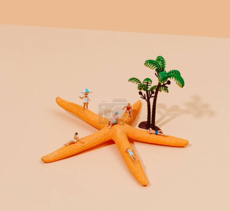 Photo for Miniature people, in swimsuit, relaxing on a starfish, next to some miniature palm trees, on a pale brown surface, against a pale brown background - Royalty Free Image