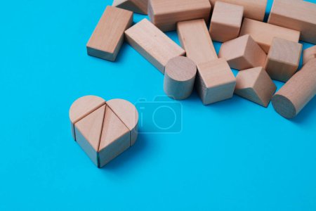 Photo for A heart made with some wooden building blocks on a blue background next to some more building blocks - Royalty Free Image
