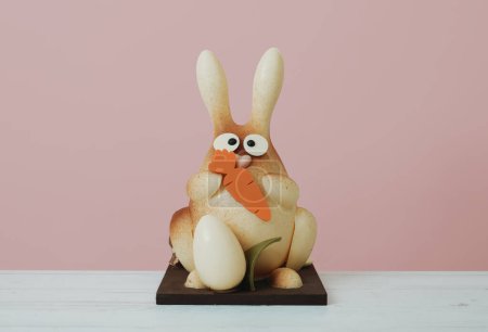 Téléchargez les photos : Un lapin de Pâques en chocolat comme moine de pascua espagnol, une confiserie traditionnelle donnée par les parrains au filleul à Pâques, sur une table en bois sur un fond rose - en image libre de droit