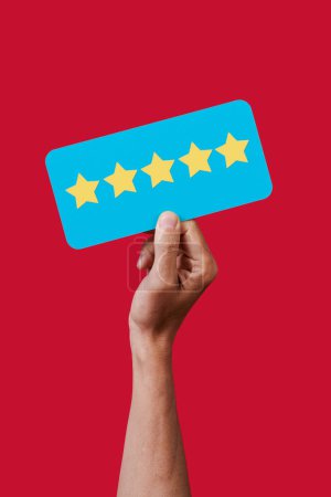 Photo for Closeup of the hand of a man holding a blue sign with five stars, from a five star rating scale, on a red background - Royalty Free Image