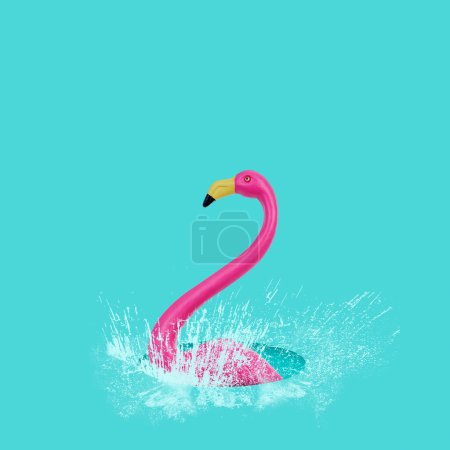 Photo for Closeup of a fake pink flamingo splashing in a puddle of water, on a blue background - Royalty Free Image