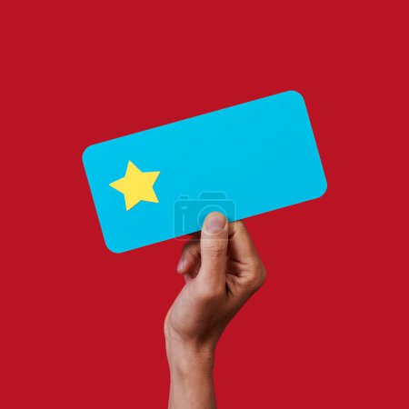 Téléchargez les photos : Un homme tient un signe bleu avec une seule étoile, sur une échelle de notation de cinq étoiles, sur un fond rouge - en image libre de droit