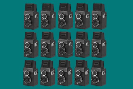 Téléchargez les photos : Un motif de certaines caméras de cinéma rétro noir moyen format disposées en différentes lignes sur un fond bleu - en image libre de droit
