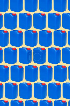 Foto de Un patrón de algunos bidones de plástico azul, con tapas rojas, dispuestos en diferentes líneas sobre un fondo verde pálido - Imagen libre de derechos