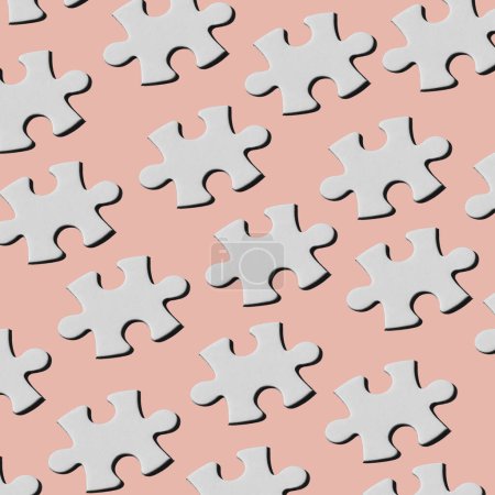 Foto de Un patrón de piezas de rompecabezas blanco dispuestas en diferentes líneas sobre un fondo rosa pálido - Imagen libre de derechos