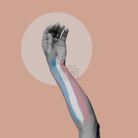 Foto de El brazo de una persona en blanco y negro con una bandera de orgullo transgénero pintada en ella, sobre un fondo rosa - Imagen libre de derechos
