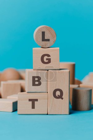 Téléchargez les photos : Gros plan de certains blocs de construction en bois de formes différentes formant l'acronyme LGBTQ, sur un fond bleu - en image libre de droit