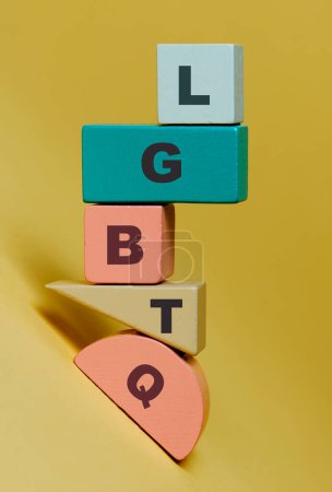 Photo for The word LGBTQ written in wooden building blocks with different colors and shapes on a yellow background, depicting the concept of diversity - Royalty Free Image