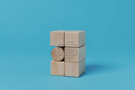 Foto de Un bloque de construcción cilíndrico en una pila de bloques de construcción rectangulares, sobre un fondo azul - Imagen libre de derechos