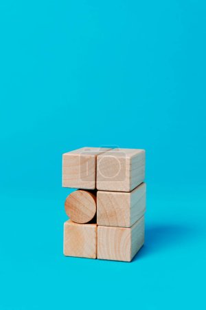 a cylindrical toy block in a stack of rectangular toy blocks, on a blue background with some blank space on top