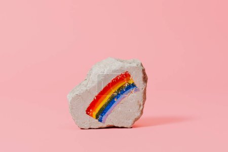 Foto de Una bandera arcoíris pintada sobre una roca, sobre un fondo rosa - Imagen libre de derechos