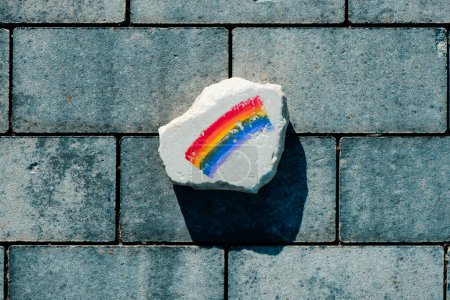 Foto de Vista de ángulo alto de una roca con una bandera de arco iris pintada en ella, en el pavimento de una calle - Imagen libre de derechos