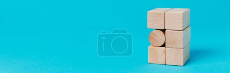 Téléchargez les photos : Un bloc de construction cylindrique dans une pile de blocs de construction rectangulaires, sur un fond bleu, dans un format panoramique à utiliser comme bannière Web ou en-tête - en image libre de droit