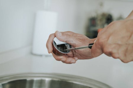 Foto de Primer plano de un hombre caucásico usando un cuchillo para vaciar el café molido de una cápsula usada para reciclar la cápsula - Imagen libre de derechos
