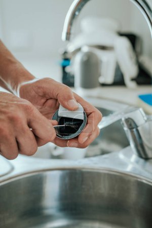 Téléchargez les photos : Un homme caucasien dans la cuisine vide le café moulu utilisé d'une capsule pour recycler la capsule - en image libre de droit