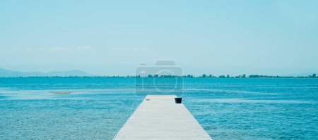 Foto de Un muelle de madera solitario que conduce al agua, en un día de verano, en un formato panorámico para usar como banner web o cabecera - Imagen libre de derechos