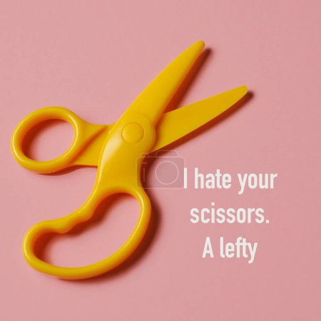 Photo for High angle view of a pair of yellow scissors for right-handers and the text I hate your scissors, a lefty, on a pink background - Royalty Free Image