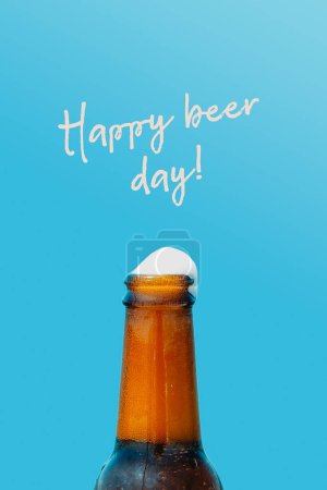 Téléchargez les photos : Gros plan d'une bouteille de bière rafraîchissante contre le ciel bleu et le texte bonne journée de bière sur le dessus - en image libre de droit