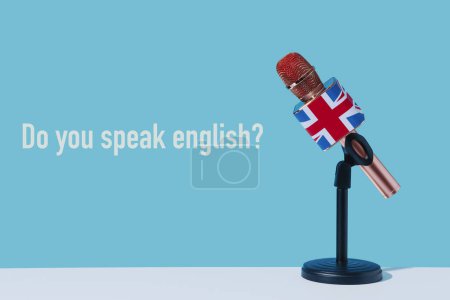 Téléchargez les photos : La question parlez-vous anglais et un microphone modelé avec la prise d'union, le drapeau du royaume uni, placé sur un support noir, sur un fond bleu - en image libre de droit