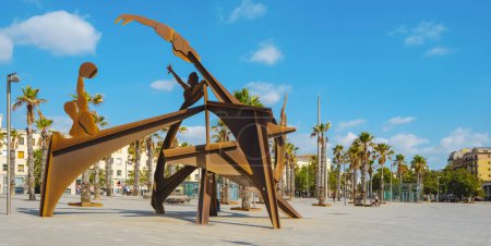 Foto de Barcelona, España - 27 de julio de 2023: Vista panorámica de la plaza Placa del Mar, en La Barceloneta, Barcelona, España, con la escultura Homenatge a la Natacio a la izquierda en primer plano - Imagen libre de derechos