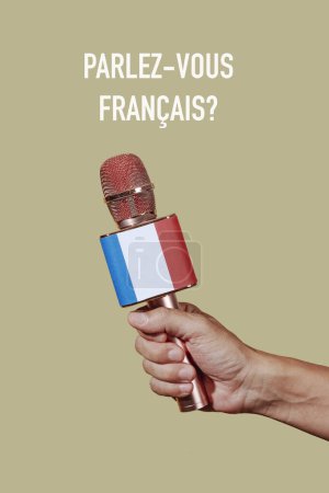 Téléchargez les photos : Gros plan d'un homme tenant un microphone orné du drapeau de la france et la question parlez-vous français écrit en français sur un fond brun pâle - en image libre de droit