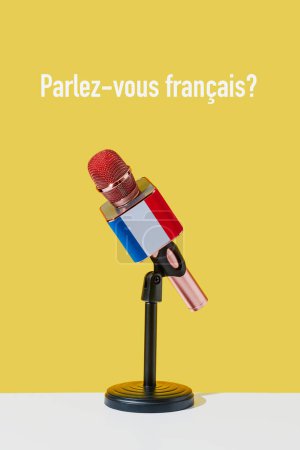 Téléchargez les photos : Un microphone avec le drapeau de france, sur un support noir placé sur une surface blanche, et la question parlez-vous français écrit en français sur un fond jaune - en image libre de droit