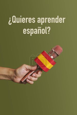 Téléchargez les photos : Un homme tient un microphone avec le drapeau de l'Espagne et la question voulez-vous apprendre l'espagnol écrit en espagnol devant un fond vert - en image libre de droit