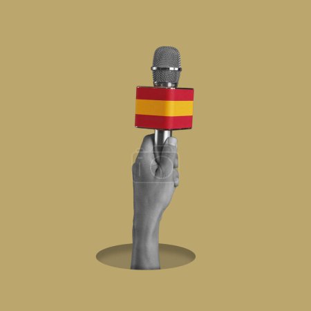 Téléchargez les photos : La main d'un homme, en noir et blanc, tenant un microphone orné du drapeau de l'Espagne, sur un fond brun pâle - en image libre de droit