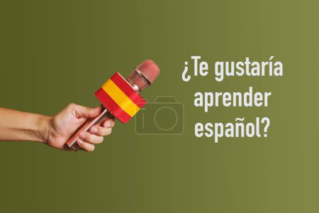 Téléchargez les photos : Homme tenant un microphone avec le drapeau de l'Espagne et la question aimeriez-vous apprendre l'espagnol écrit en espagnol sur un fond vert - en image libre de droit
