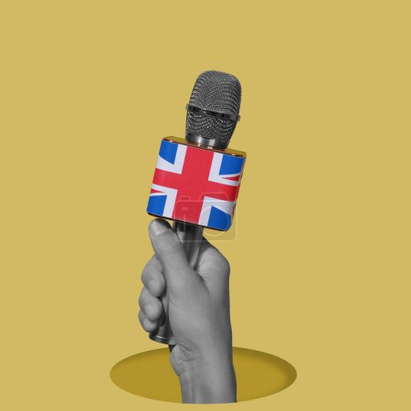 Téléchargez les photos : La main d'un homme, en noir et blanc, tenant un microphone orné du drapeau du royaume uni, regardant par un trou, sur un fond jaune - en image libre de droit