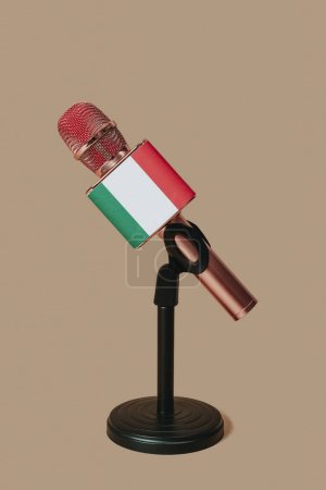 Téléchargez les photos : Un microphone à motifs avec le drapeau de l'Italie, dans un support de bureau noir placé sur un fond brun - en image libre de droit