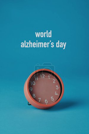 Téléchargez les photos : Une horloge rose sans aiguilles et le monde du texte alzheimers jour sur un fond bleu - en image libre de droit