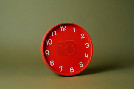 Foto de Un reloj rojo sin manecillas sobre un fondo verde oliva - Imagen libre de derechos
