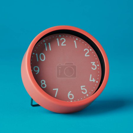 Foto de Primer plano de un reloj rosa sin manos sobre un fondo azul - Imagen libre de derechos