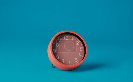 Photo for A pink clock without hour or minute hands on a blue background with some blank space around it - Royalty Free Image