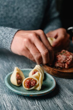 Photo for A man stuffing some Catalan galets with some ground meat, to prepare sopa de galets or escudella de Nadal, typically eaten on Christmas in Catalonia, Spain - Royalty Free Image