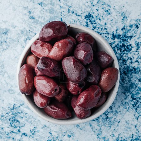 Photo for High angle view of a white ceramic bowl with some kalamata olives on a stone surface - Royalty Free Image