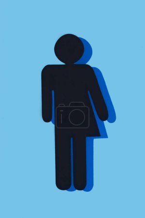 Photo for Closeup of a black gender neutral icon, with a dark blue shadow, on a blue background - Royalty Free Image