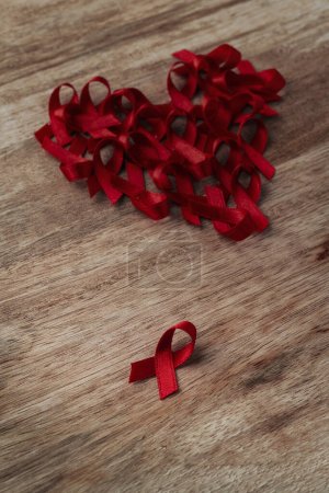 Téléchargez les photos : Gros plan de quelques rubans rouges de sensibilisation, pour la lutte contre le sida, disposés formant un cœur sur une surface en bois - en image libre de droit