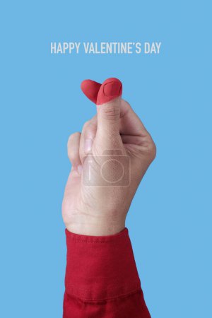 Photo for Closeup of the hand of a man in red doing the finger heart gesture, with the tips of his fingers painted red, and the text happy valentines day on a blue background - Royalty Free Image