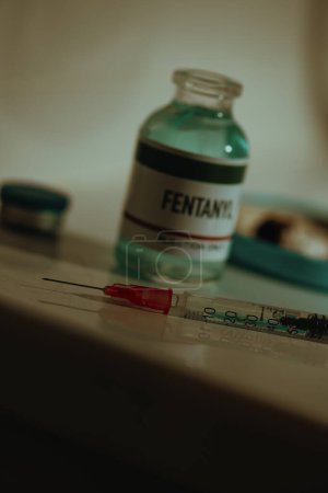 Photo for An open simulated vial of fentanyl and a syringe on top of the cistern of a sordid toilet in a restroom, with a dramatic lighting - Royalty Free Image