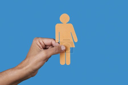 Photo for A caucasian person holds a homemade yellow gender neutral icon in front of a blue background - Royalty Free Image