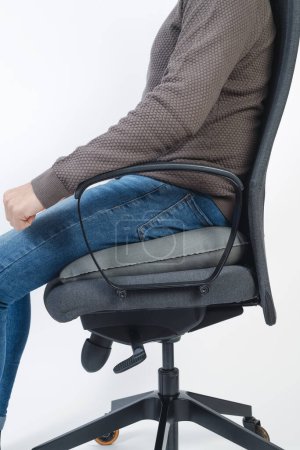 Photo for Closeup of a man sitting on an inflatable ring cushion on an office chair - Royalty Free Image