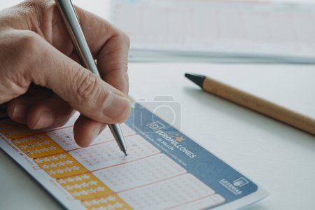 Photo for Barcelona, Spain - February 8, 2024: A man picks numbers from a Euromillones lottery ticket, checking some checkboxes with a pen. Euromillones is a European draw - Royalty Free Image