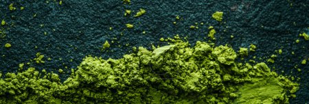 Photo for High angle view of some matcha powder tea on a dark textured surface, in a panoramic format to use as web banner or header - Royalty Free Image