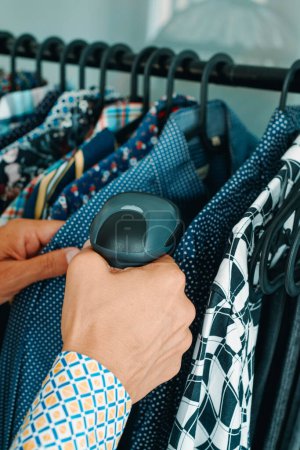 Foto de Un asistente de tienda utiliza un escáner de código de barras portátil para escanear la información de una camisa en una tienda de ropa - Imagen libre de derechos